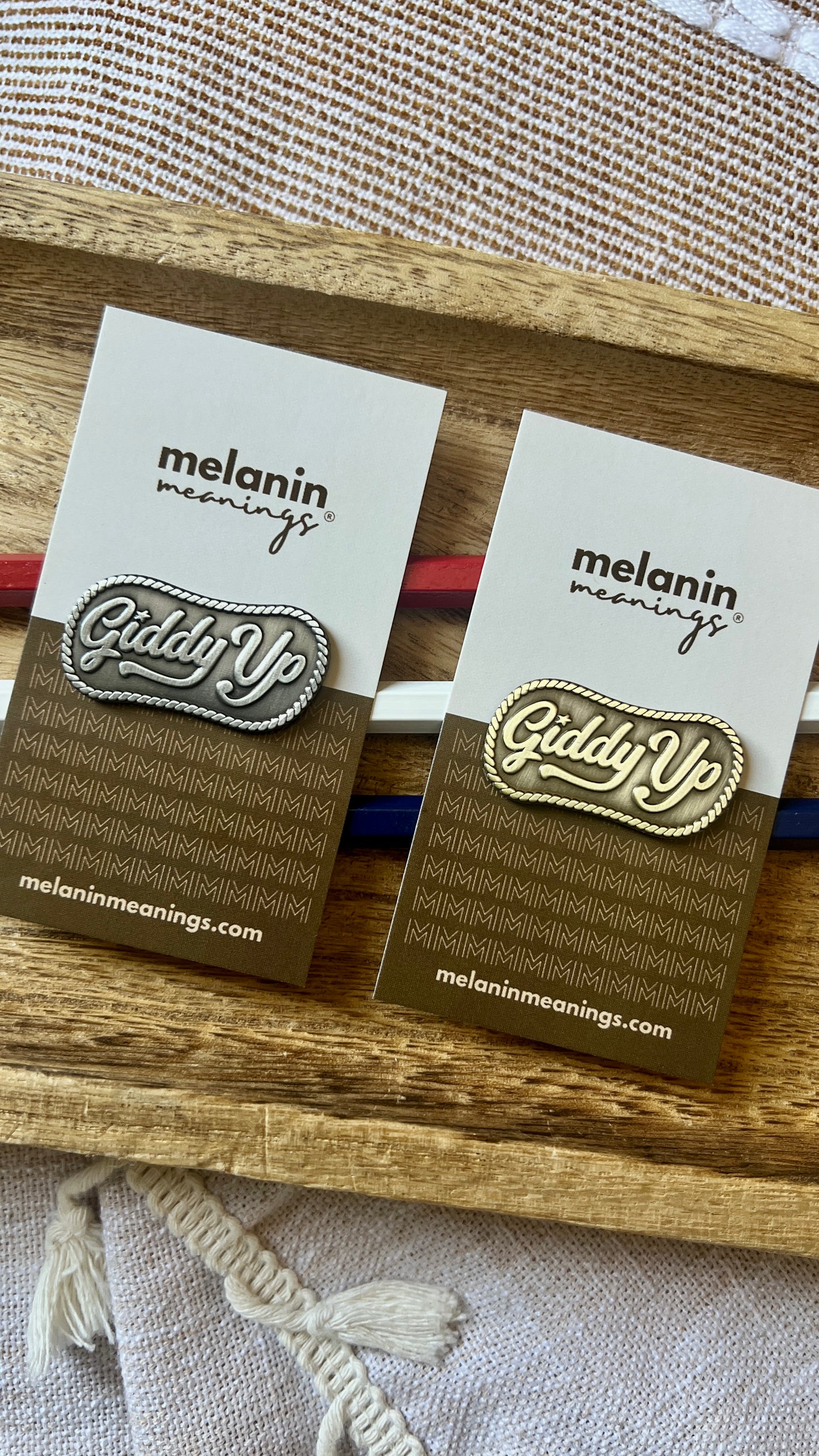 Giddy Up enamel pin in antique silver and antique gold shown side by side on Melanin Meanings backing cards